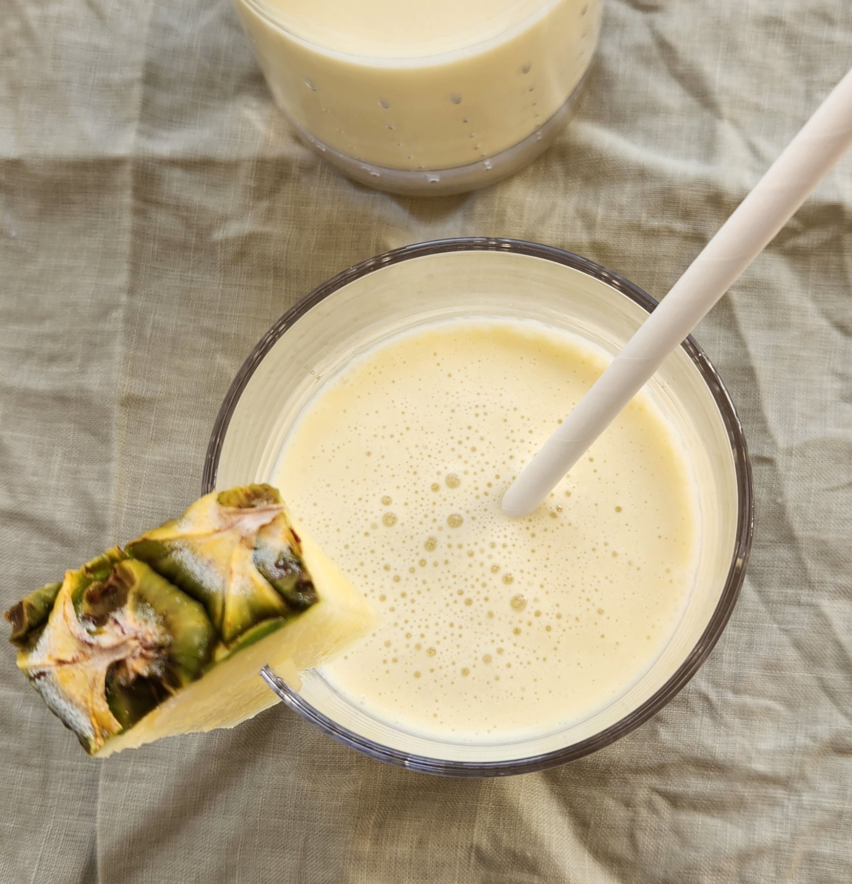 overhead image of the pina colada smoothie garnished with pineapple and straw